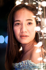 Portrait of Asian woman with decorative warm lights at night