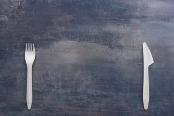 Natural cutlery - wooden knife and fork with copy space between them. Marble black kitchen counter.