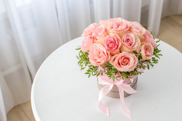 Beautiful bouquet of pink roses in a festive round box on a white table. Gift for holiday, birthday, Wedding, Mother's Day, Valentine's day, Women's Day.  Flowers in a hat box.