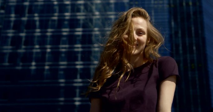 coquettish woman with light red hair is grimacing in front of camera on urban background