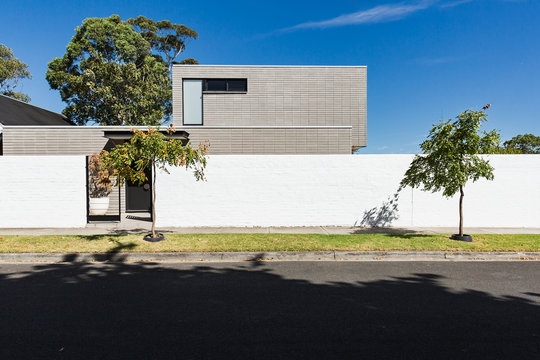 Architectural home exterior of stacked pattern grey concrete brick and high front fence