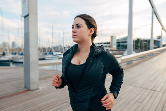 Plus size woman running at seaside on a pier.