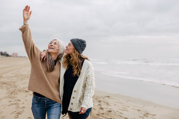 Senior woman and her daughter enjoying a winter day on the beach.