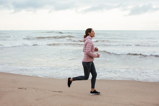 Side view of an active woman running on the beach.