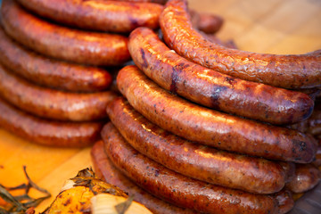 Several units of grilled German sausage on a wooden platter