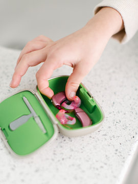 Young girl taking her pink hearing aids out of case