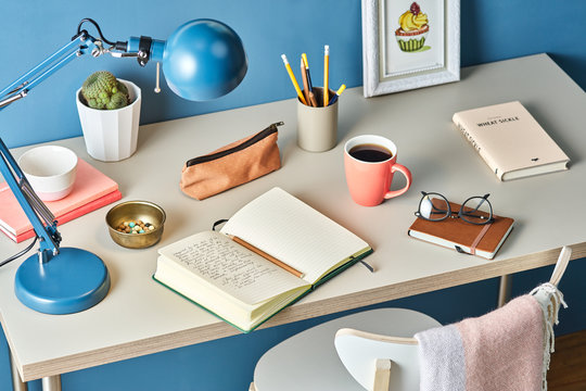 Modern desktop with notebook, cup of coffee, lamp and stationery