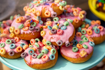 Several strawberry glazed donuts with fruit cereal toppings