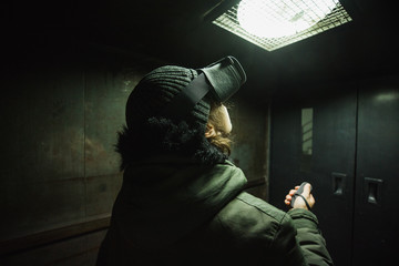 Young man using gray VR goggles finding himself in an industrial elevator