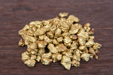 mound of gold nugget on dark wood background