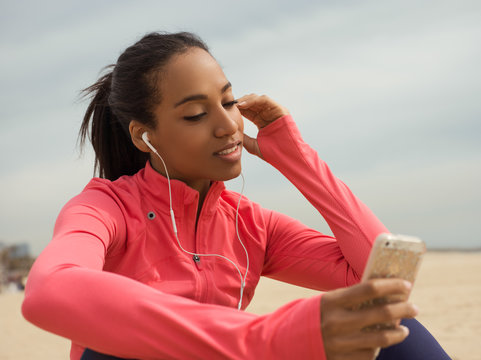 Content sportswoman with phone on beach