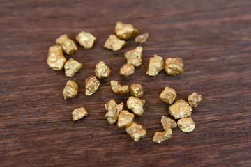 mound of gold nugget on dark wood background