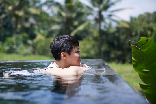 Asian woman lying comfortably in an infinity pool. Holidays in Southeast Asia