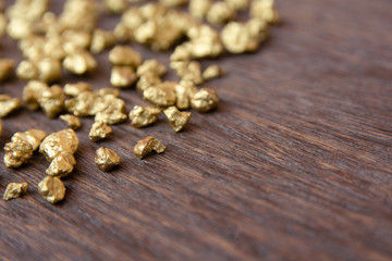 mound of gold nugget on dark wood background