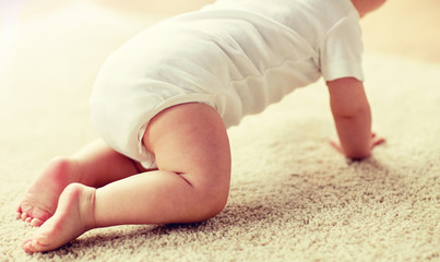 childhood, babyhood and people concept - little baby boy or girl crawling on floor at home