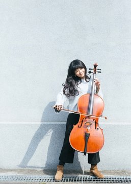 Portraits of female jazz cellist playing in outdoor space