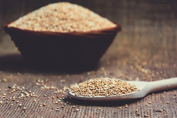 White seeds of Quinoa in a wooden spoon and a wicker bowl. Healthy nutrition and superfoods. Latin name Chenopodium quinoa. Food for gluten-free diet. Product photo