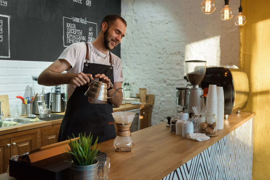 Cheerful man brewing coffee in shop