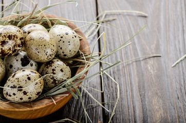 Naklejka na ściany i meble Fresh organic quail eggs in wooden bowl on rustic kitchen table. Space for text