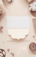 Workspace. Invitation cards, craft envelopes, cotton flower on light background. Overhead view. Flat lay, top view