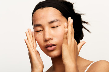 Young natural asian woman portrait applying moisturiser.