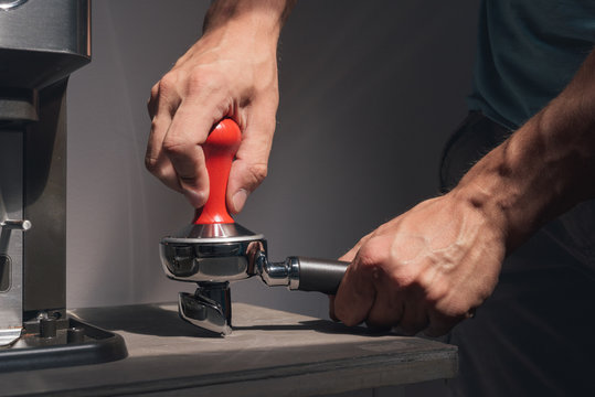 Man compressing freshly grounded coffee