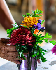 Hands working arranging colorful flowers in jars on a farmstead for a farm to table dinner