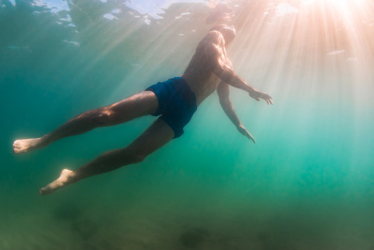 Man rises to surface to breathe while diving swimming in shallow