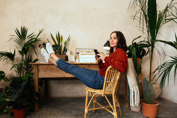 Woman using her phone in office full of plants.