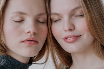 Two faces of pretty young females with closed eyes