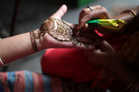 woman applying mehendi in hand in a hindu marriage occassion