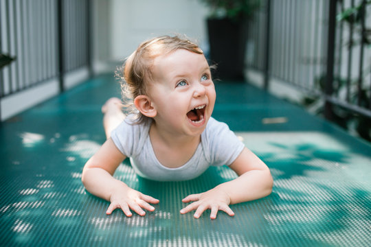Happy toddler laying on the turquoise glass floor laughing.