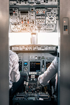 Pilot and copilot inside a cabin flying an airplane.