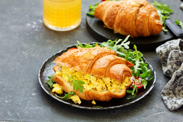 Breakfast of croissant with scrambled eggs and salad.