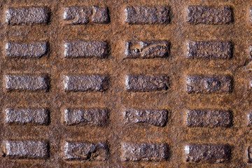 old rusty corrugated metal manhole cover, cast iron with rectangles