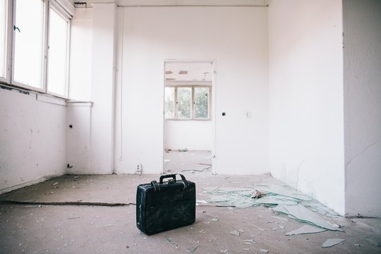 Briefcase and broken glass in white room