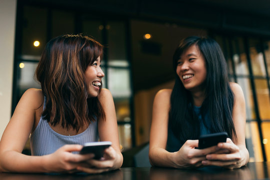 Asian Friends Women Using The Mobile In The Coffee Shop.