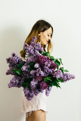Attractive girl with a bouquet of lilac on a white background