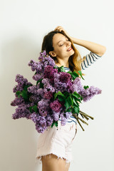 Attractive girl with a bouquet of lilac on a white background