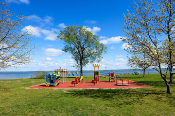 colorful children playground in the park on the sea coast under blue sky with clouds