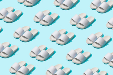 Trendy sunlight Summer pattern made with white slippers on bright light blue background. Minimal...
