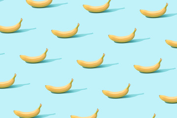 Trendy sunlight Summer pattern made with fresh banana fruit on bright light blue background. Minimal summer concept.