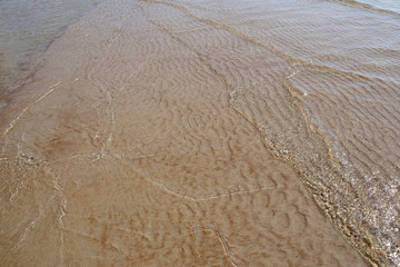 Sand texture created by sea waves on beach coast. Sand pattern under soft waves. Sand texture of Baltic sea coast.