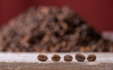 coffee beans in the foreground on wooden board, in the background mountain of coffee beans