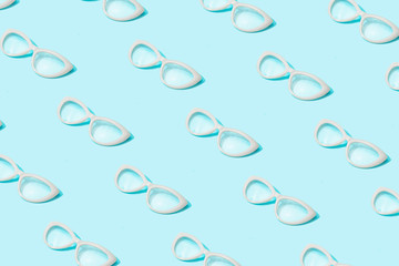 Trendy sunlight Summer pattern made with glasses on bright light blue background. Minimal summer concept.