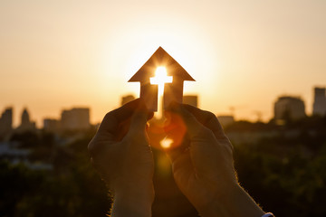 Paper house with cross in hand .
