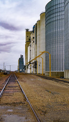 Large grain elevators with bold skies in color and black and white Railroad tracks as leading lines