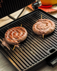 Fried spiral sausages on an electric barbecue BBQ grill. Homemade menu.