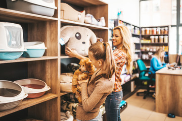 Mother and daughter with their poodle puppy in pet shop.