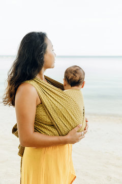 Mother with baby in sling on the beach